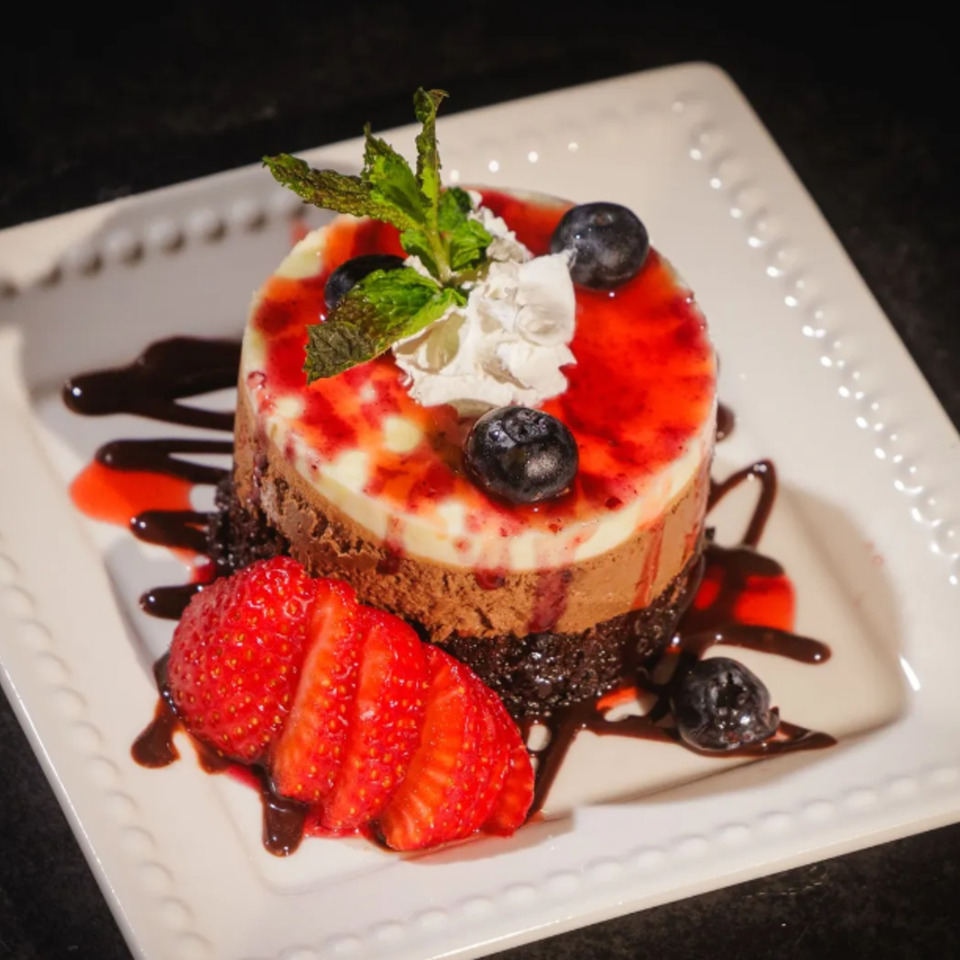Chalet's layered chocolate and vanilla dessert with strawberry sauce, blueberries, whipped cream, and mint.